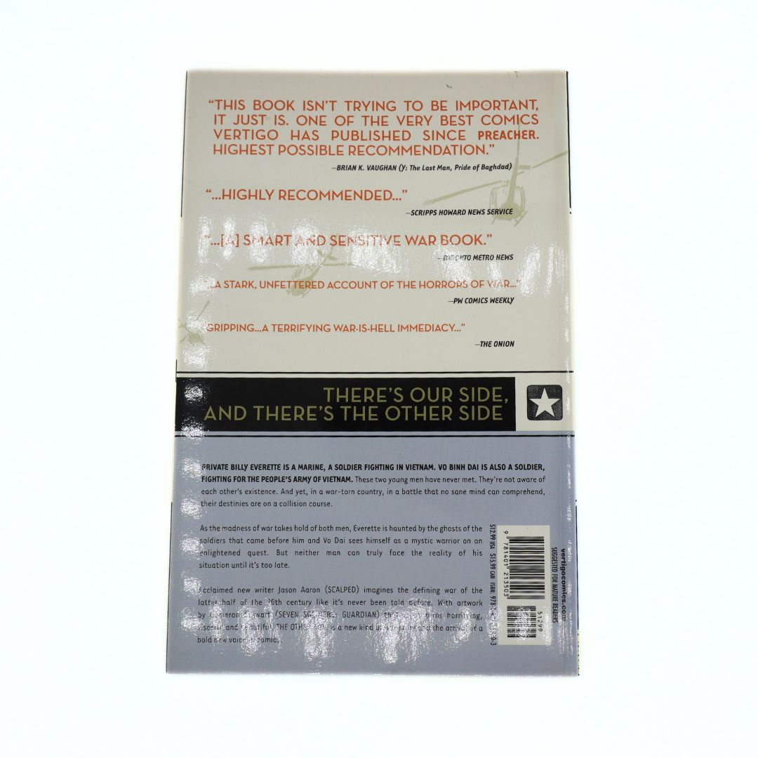 Back cover of the comic book The Other Side, with a grey and ream colour palette photographed on a white background
