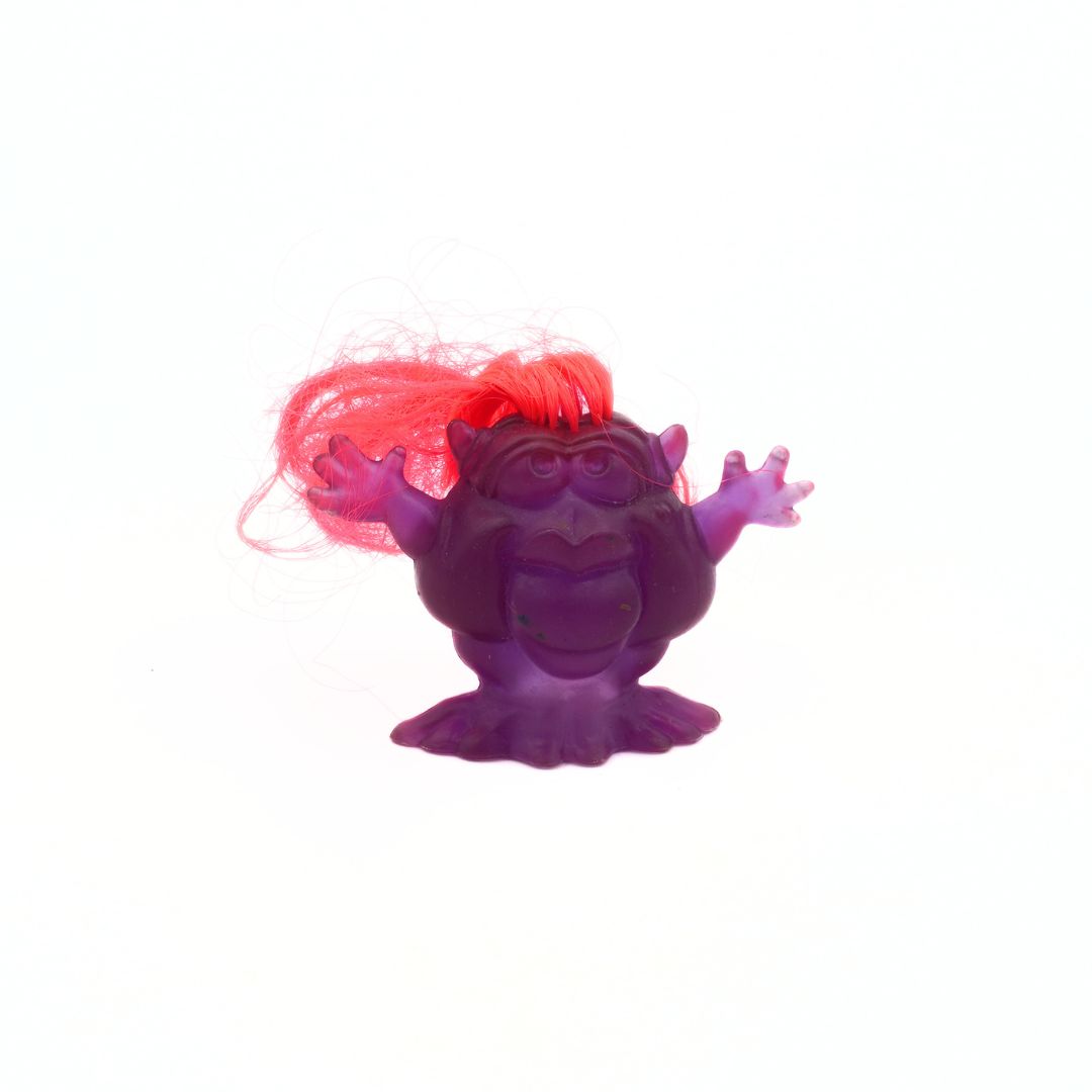 Purple toy figure with red hair on a white background