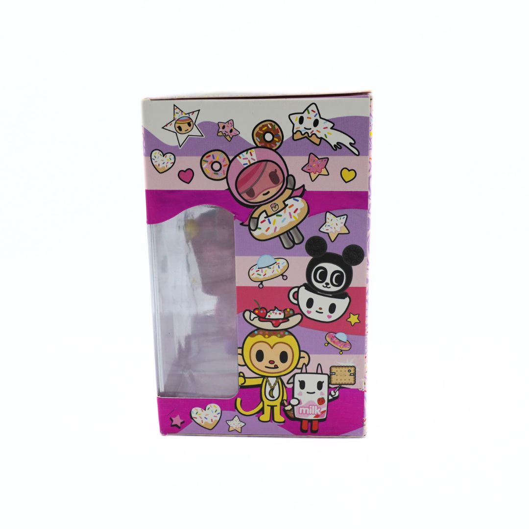 A Tokidoki collectible figure in its original packaging, featuring a clear plastic window on the front of a purple and pink illustrated box with cartoon characters.