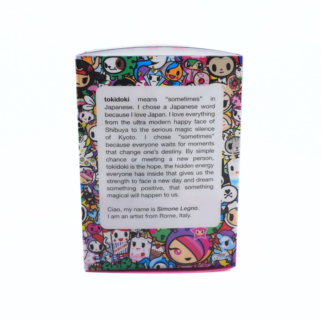 A rectangular product box with a colorful Tokidoki cartoon pattern and a large white text panel on the front, photographed against a plain white background.