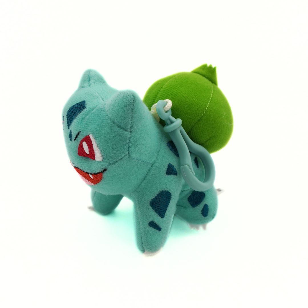 Plush keychain of a green creature with a leaf on a white background