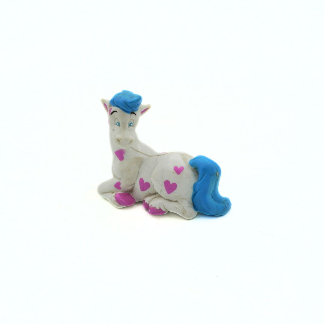 Plastic toy resembling a horse with blue hair and pink hearts on a white background