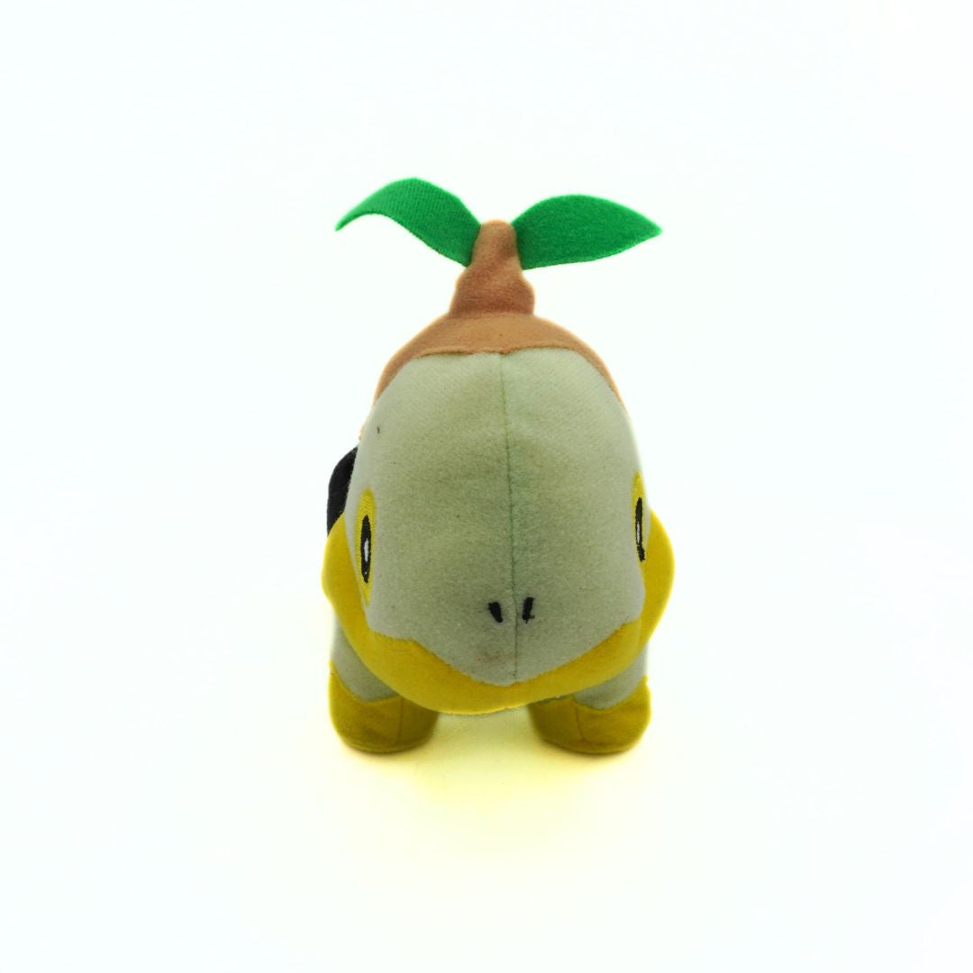 Plush toy resembling a character with a green leaf on a white background