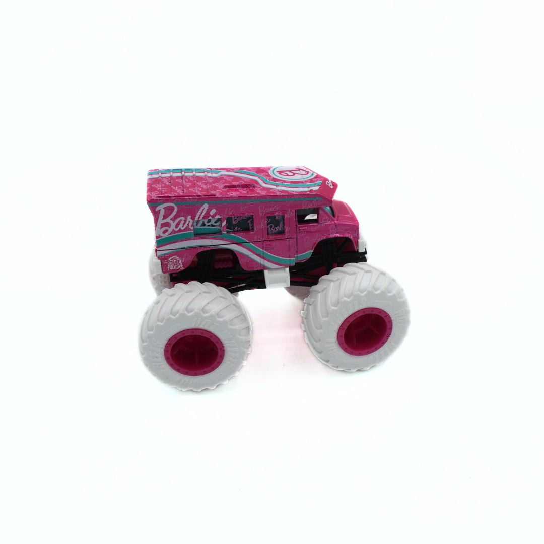 A pink toy monster truck with oversized white tires and the Barbie logo on the side, photographed on a plain white background.