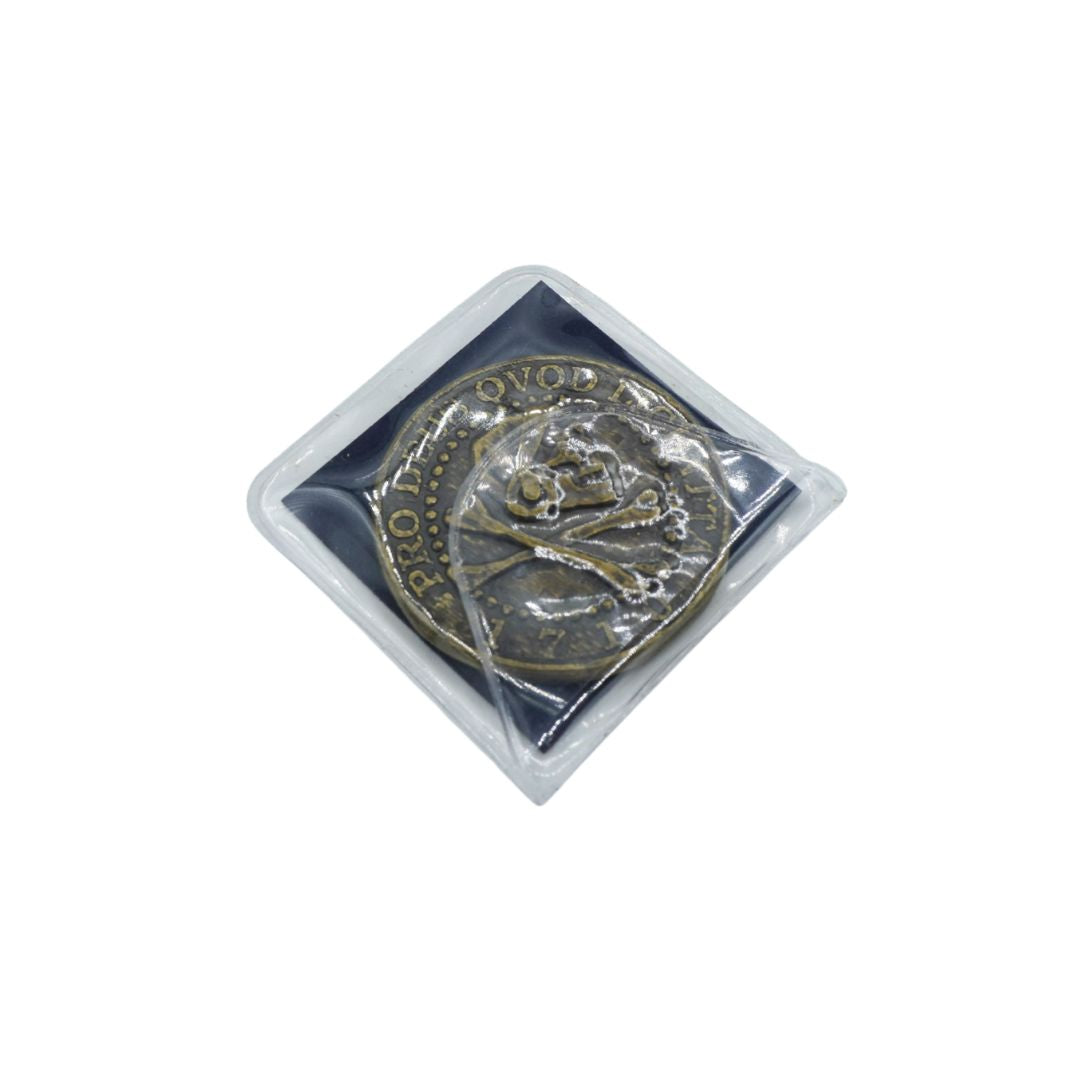 A round bronze-colored coin featuring a skull and crossbones design, sealed inside a clear plastic protective sleeve and displayed on a black backing card against a white background.