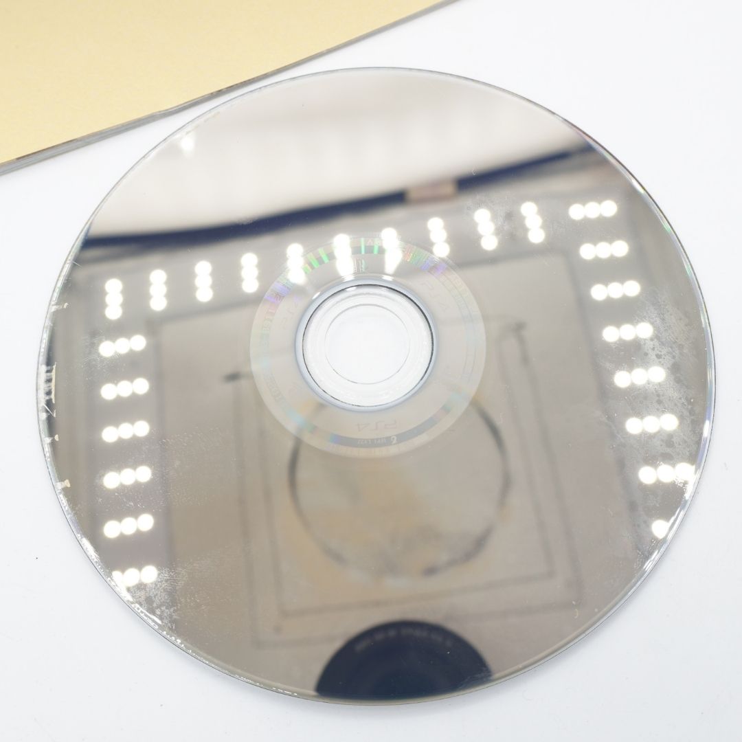 A reflective silver CD-R disc lying on a white surface, showing a faint printed track layout and bright reflections from the environment.