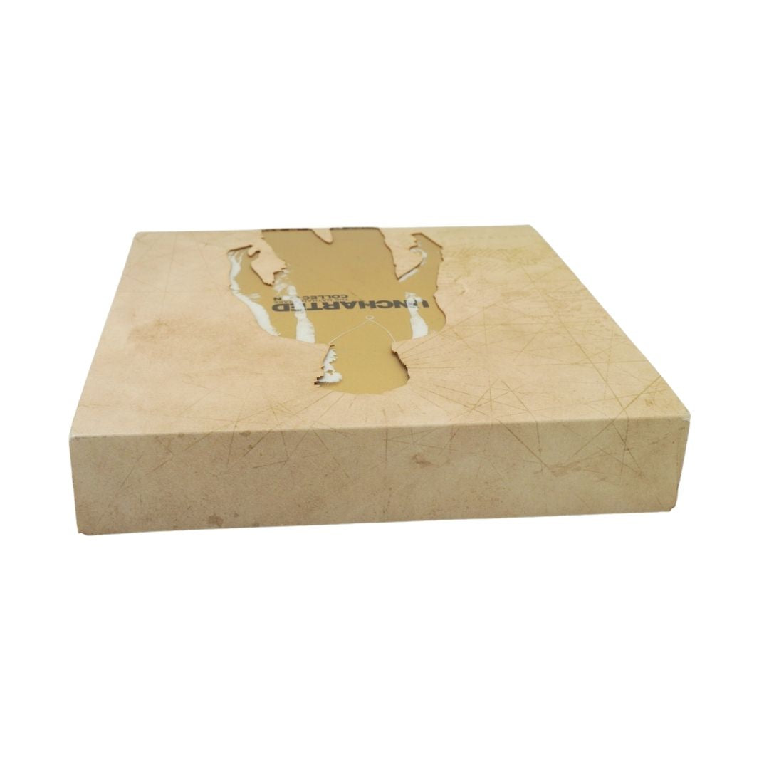 A square beige stone or marble-like decorative box with a cutout design on top and the word 'UNCHARTED' printed on the surface, shown on a plain white background.