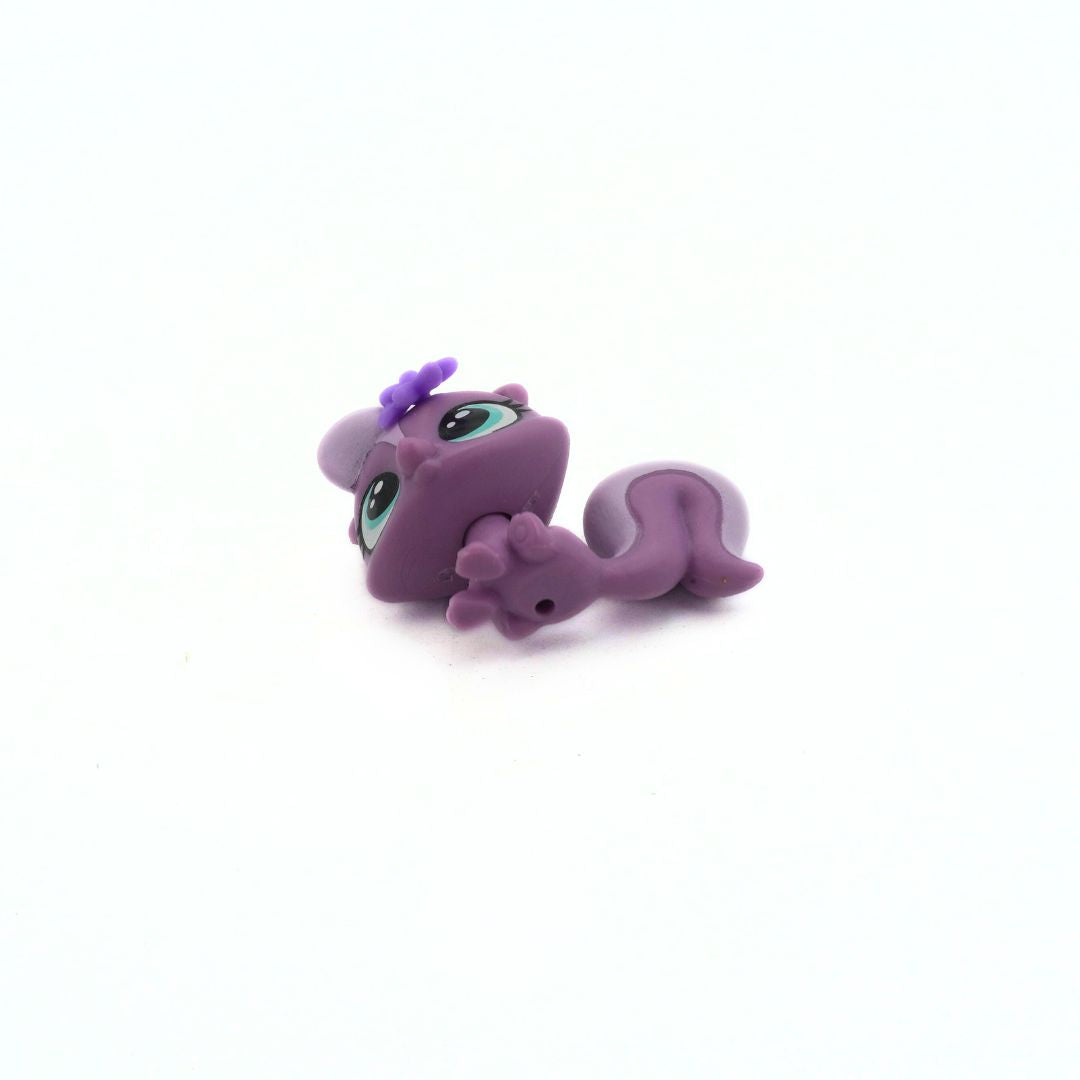 Purple toy figure of a creature with a bow on a white background
