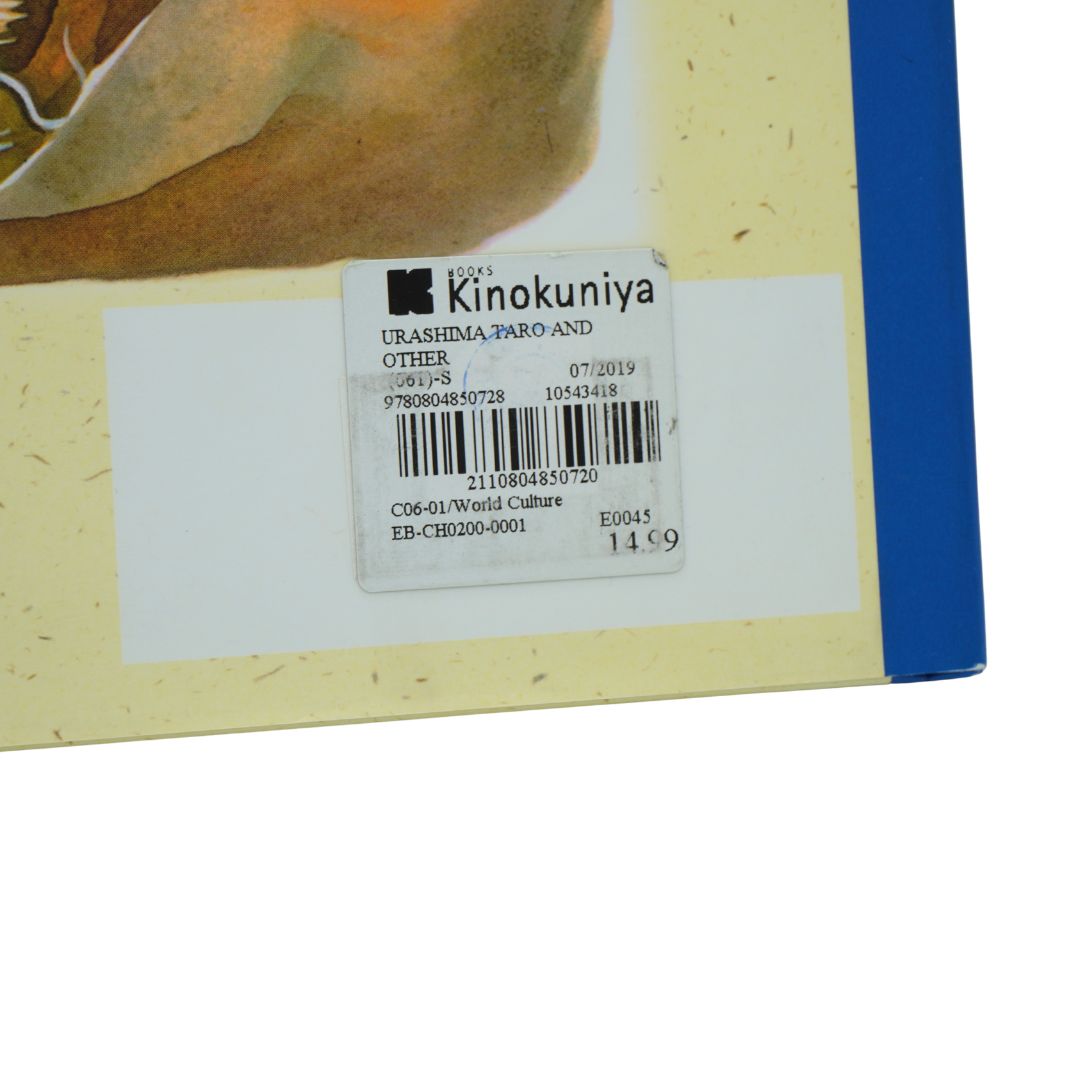 Close-up of a book cover corner showing a cream-colored illustrated background, a blue vertical edge, and a white barcode sticker with Kinokuniya text.