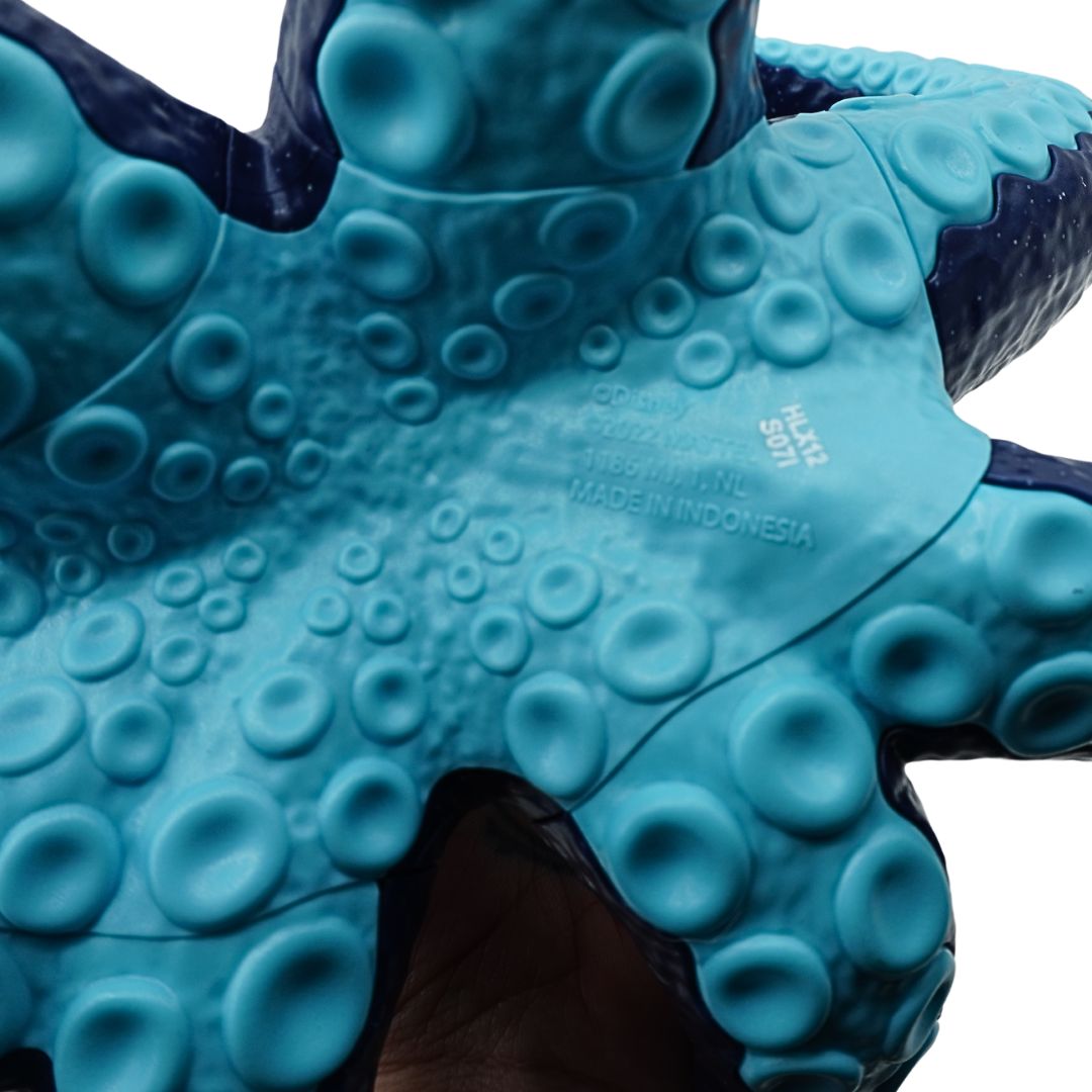Ursula doll wearing a dark blue dress and with purple hair, showing the branding information at its base
