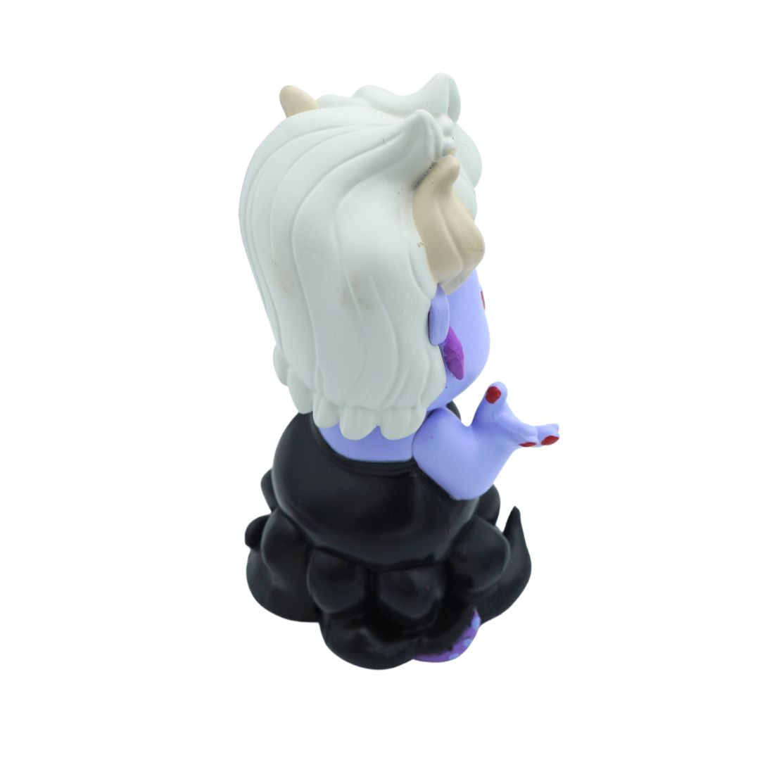 A stylized vinyl figure of Ursula seen from the back, featuring white hair, a purple face and hands, a black dress, and small red fingernails, set against a plain white background.
