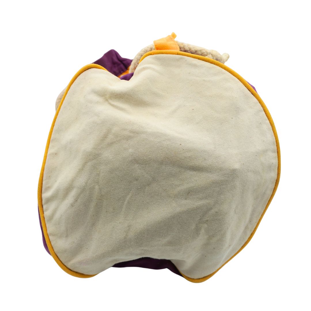 The underside of a vintage canvas bag with purple and yellow colours, on a white background