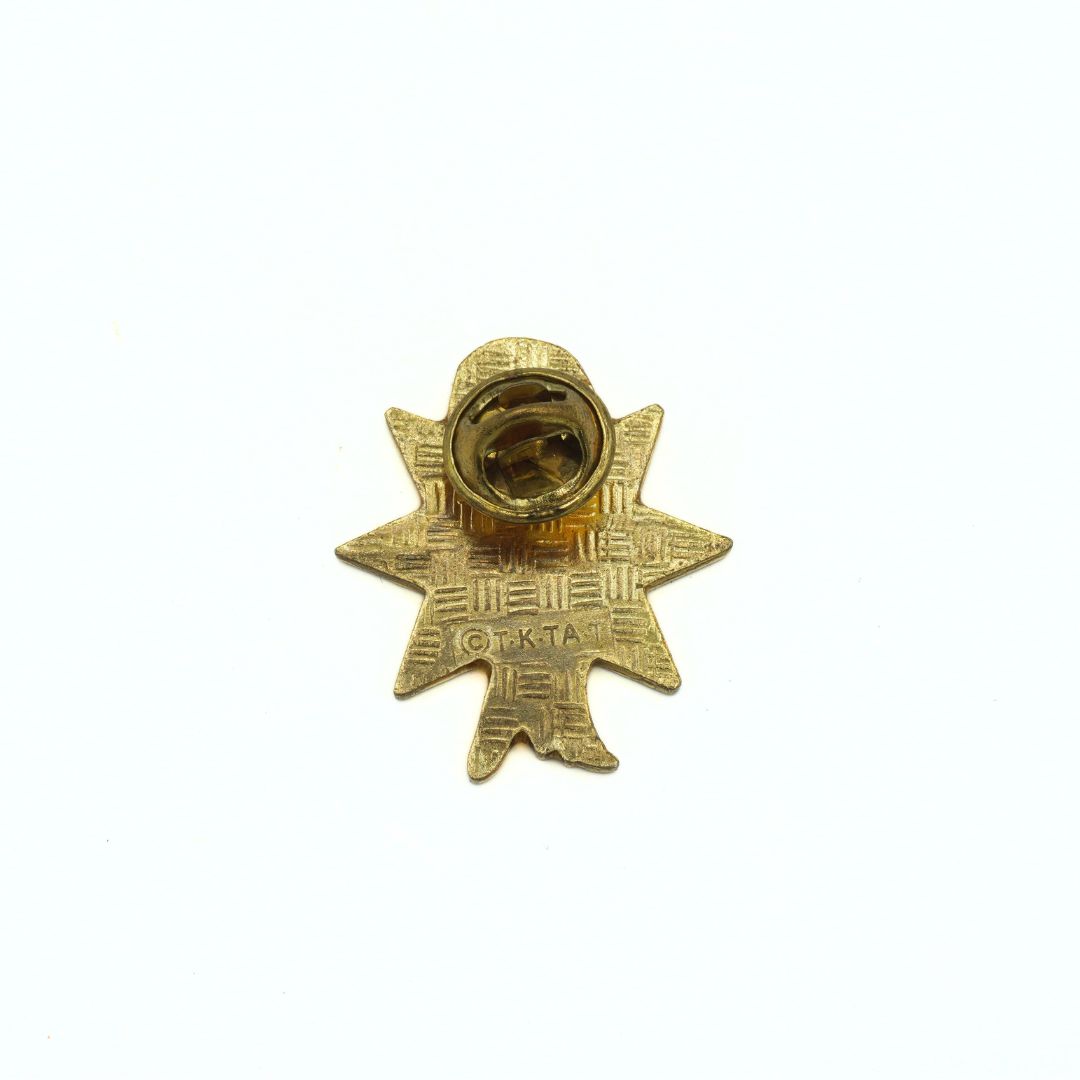 Gold star-shaped pin with a central emblem on a white background