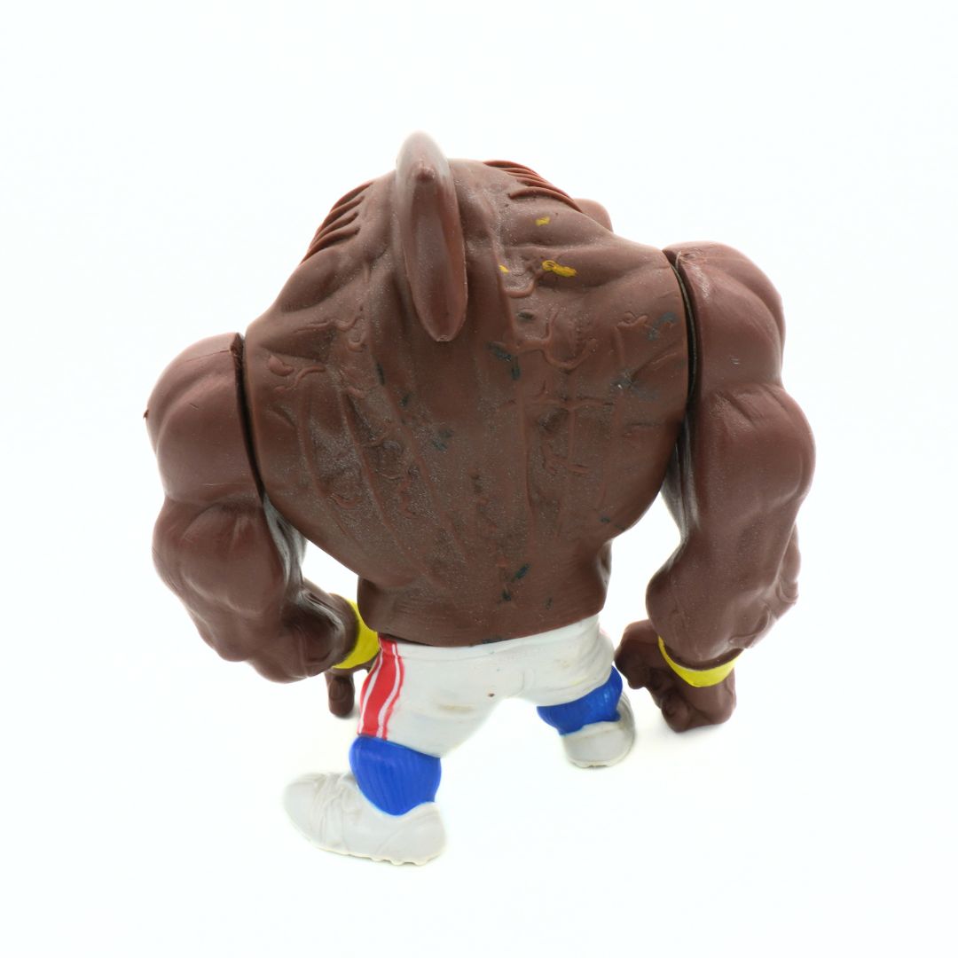 Toy figure of a muscular brown animal in a fighting stance on a white background