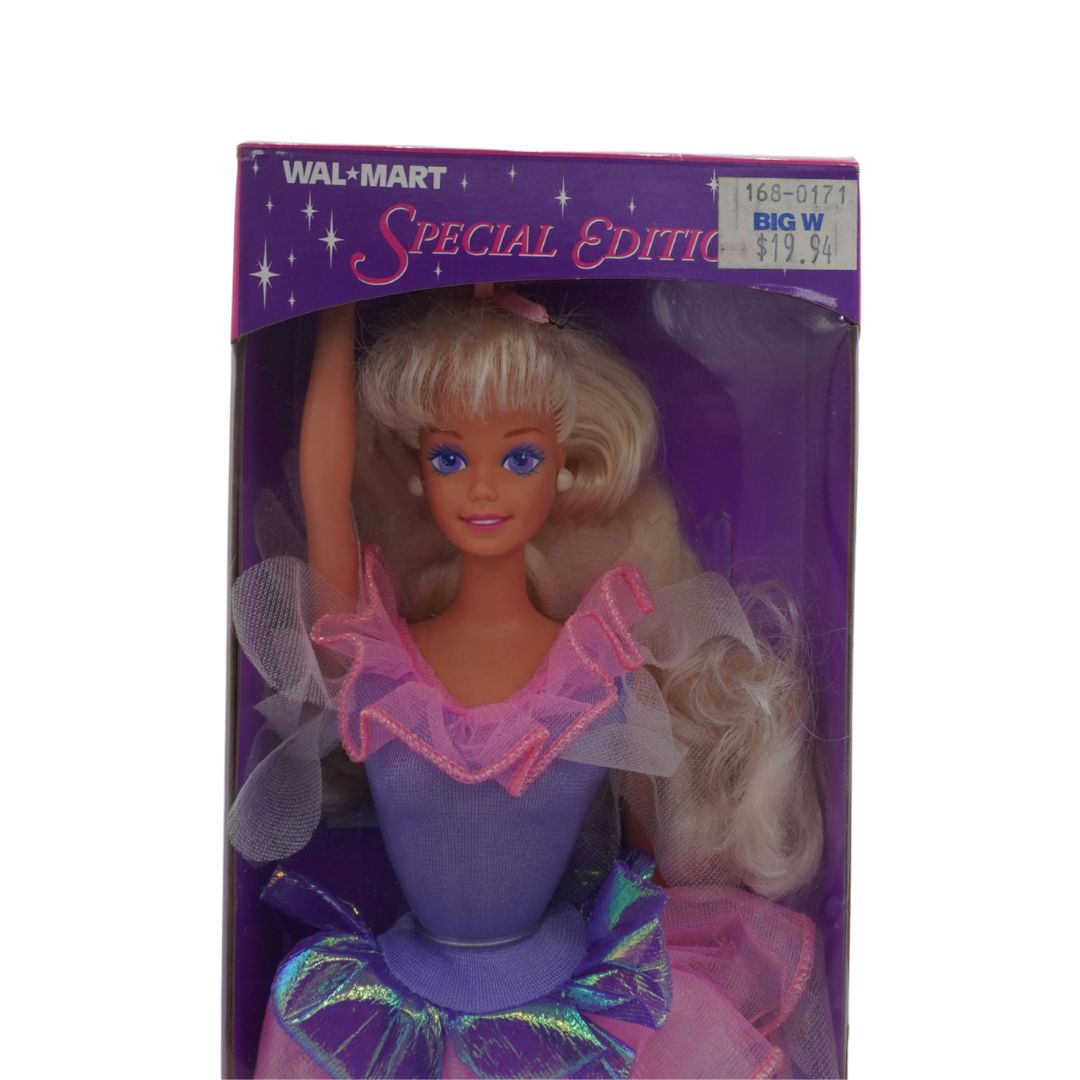 Barbie doll in a purple outfit with a pink bow in her hair, packaged in a Walmart Special Edition box.