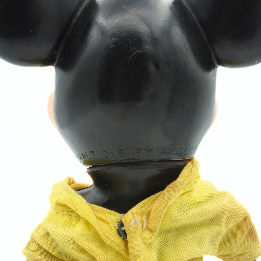 Close-up of a black Mickey Mouse figurine with a yellow shirt on a white background