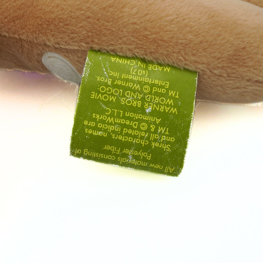 Close-up of a green label on a plush toy, with 'Warner Bros' branding visible.