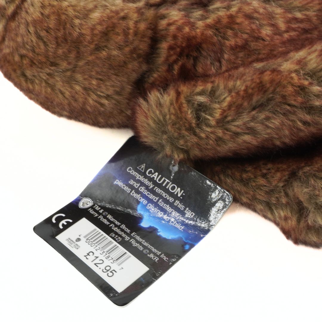 Close-up of a brown plush toy with a label on a white background