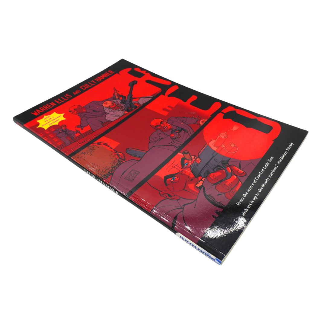 A comic book titled 'Red' by Warren Ellis, featuring a bold red and black comic-style cover with illustrated figures and a yellow starburst, photographed on a plain white background.
