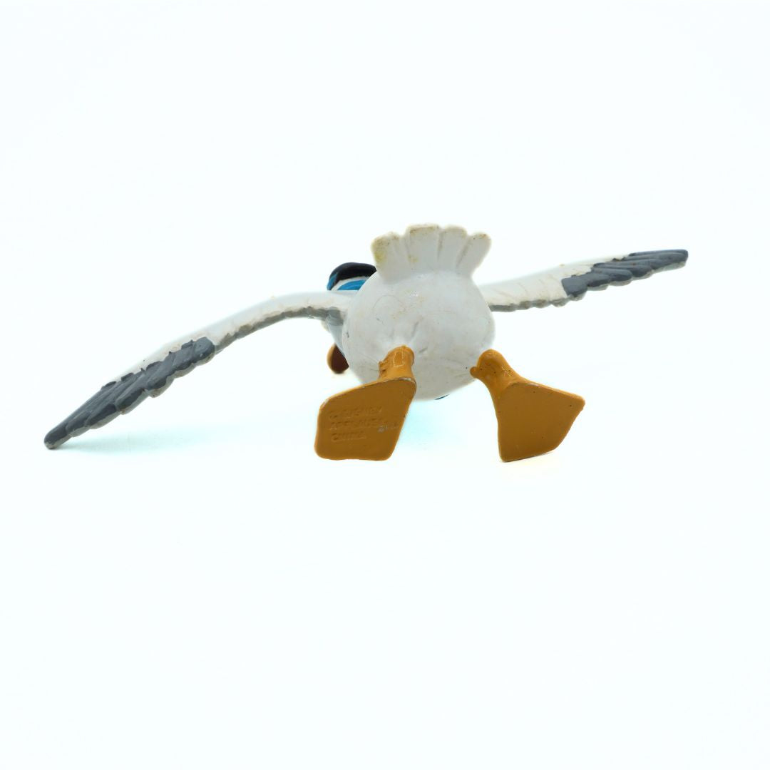 Plastic toy of a bird with white body, gray wings, and yellow feet on a white background