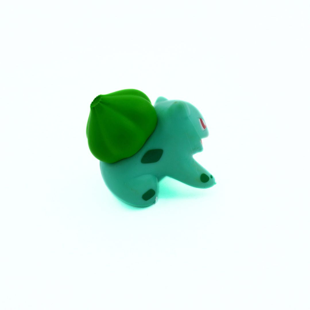 Small green toy figure with a leaf on a white background