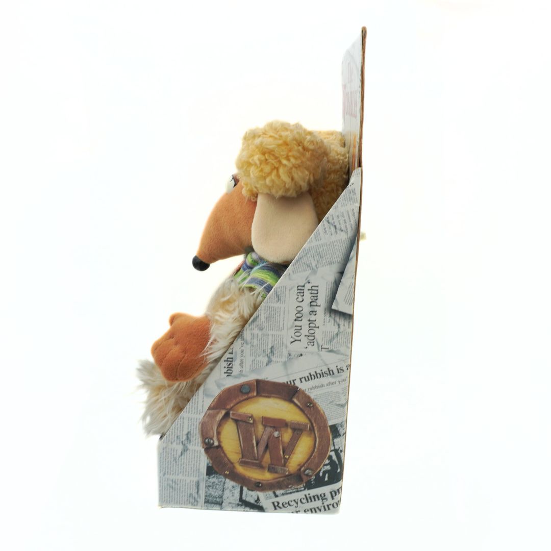 Plush Wombles toy with a newspaper packaging featuring a logo.