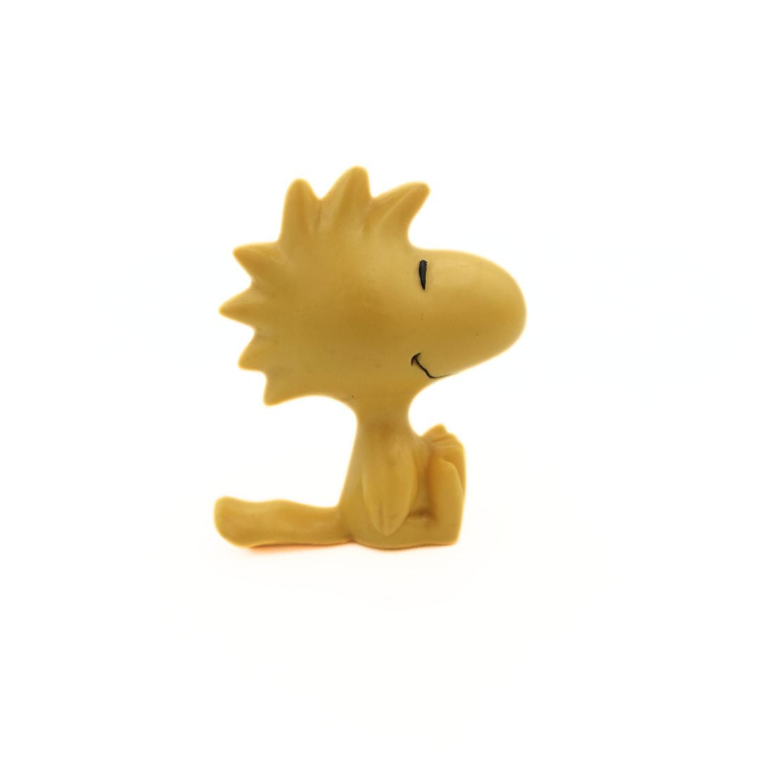 Side on photo of a PVC figurine of the. Woodstock character from Peanuts.