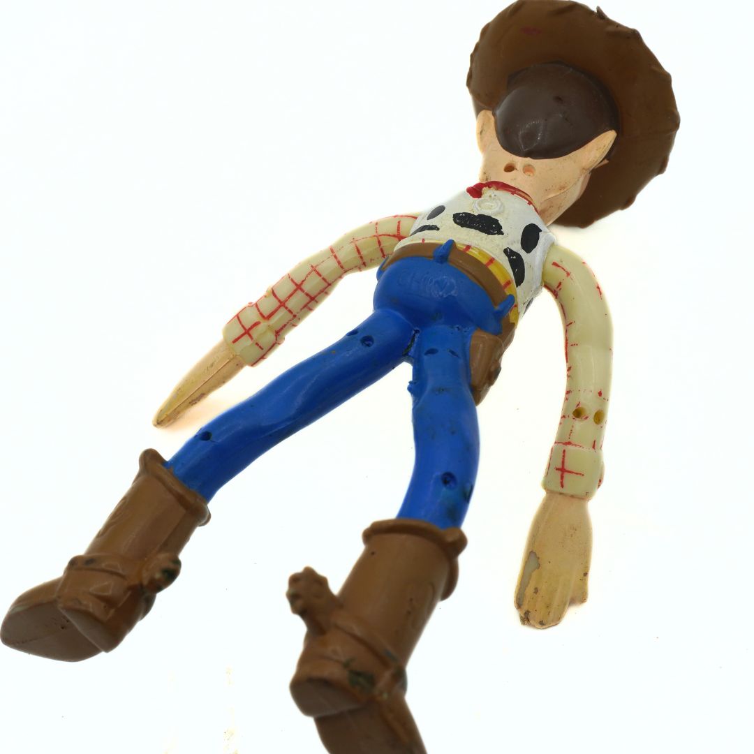 Toy figure of a cowboy character with a white shirt, blue pants, and brown boots on a white background.