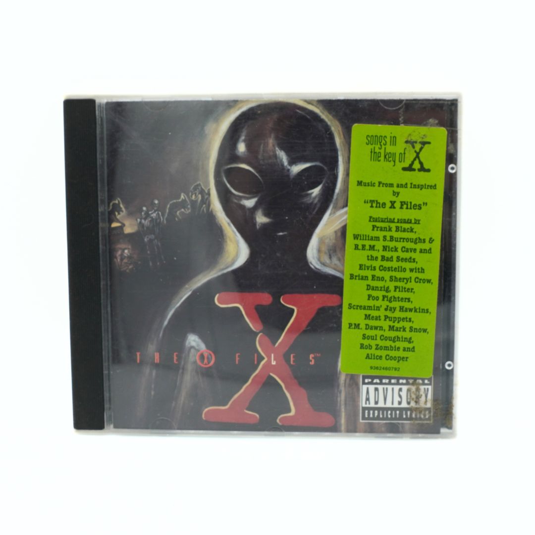 A CD album for 'The X-Files' titled 'The Key to X' with a black-and-white alien graphic, a large red 'X', and a bright green tracklist sticker on the right side.