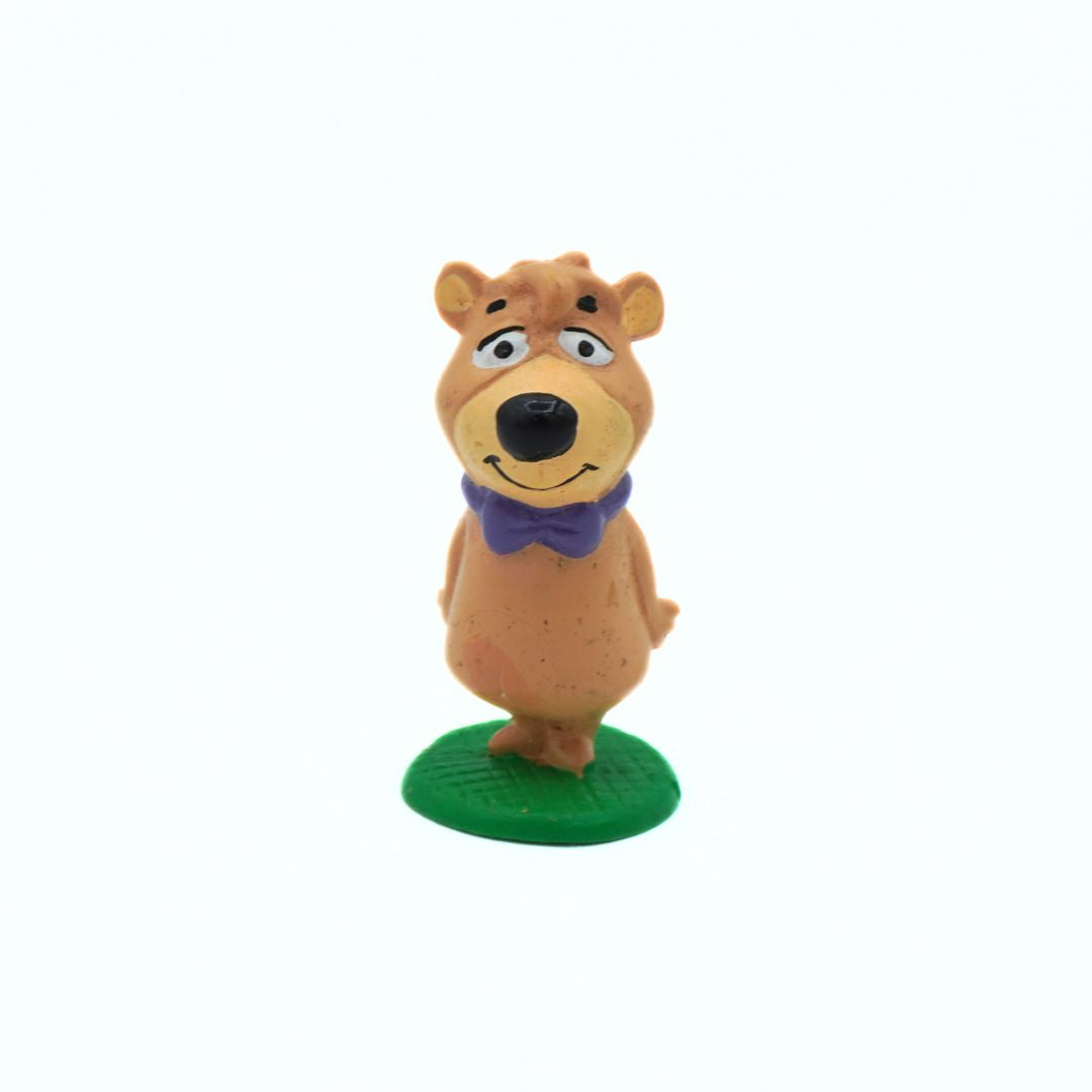Cartoon bear figurine with a purple bow tie on a white background