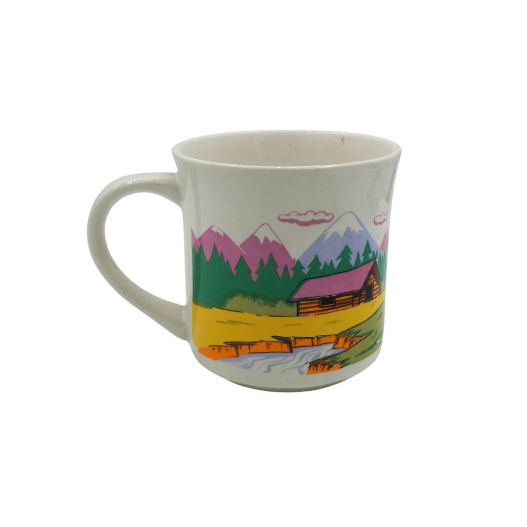 Mug with a scenic design of mountains, trees, and a cabin on a white background